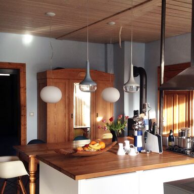 Küchenzeile im Vordergrund mit Geschirr, Obstschale und Vasen auf der Theke, im Hintergrund ein Schrank mit Spiegel