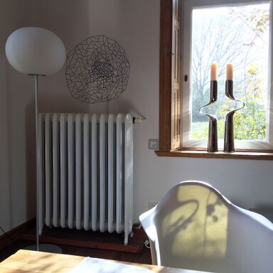 Stimmungsvolles Licht aus dem Fenster zum Garten mit einem Kerzenleuchter von Mikaela Dörfel Design auf dem Fensterbrett