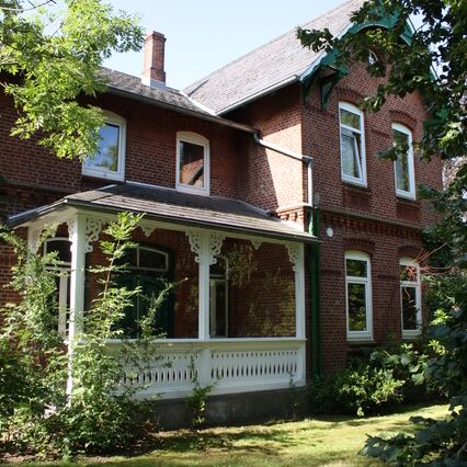 Der Windfang des Werkguts von außen, umgeben von Bäumen