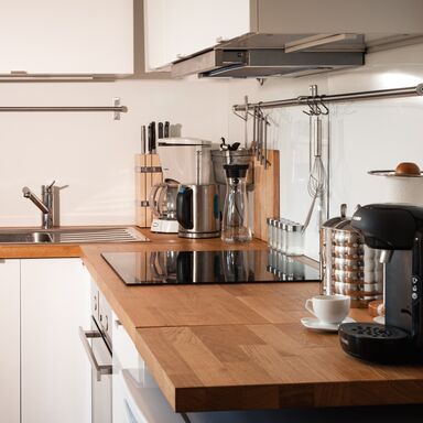 Wohnküche im Loft im Haupthaus Wohnküche über Eck im Loft im Haupthaus mit heller Holzplatte, Kaffeemaschine, Cerankochfeld und Spüle