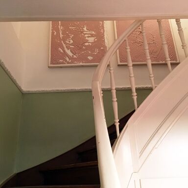 Im Treppenaufgang des Haupthauses hängen zwei große Kunstwerke aus Linol auf Leinwand